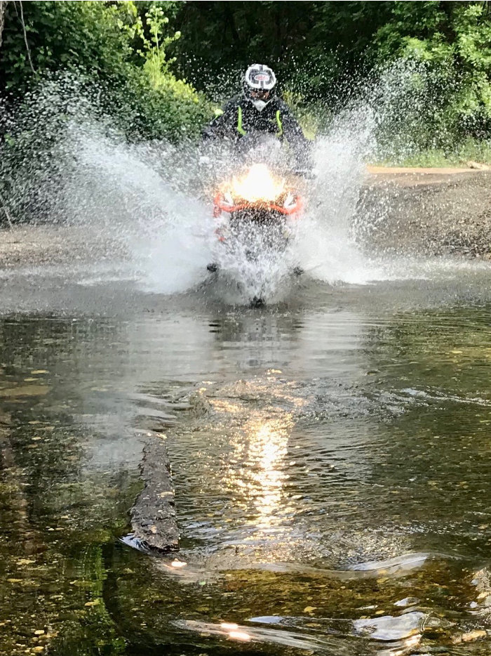 Man riding motorcycle through creek